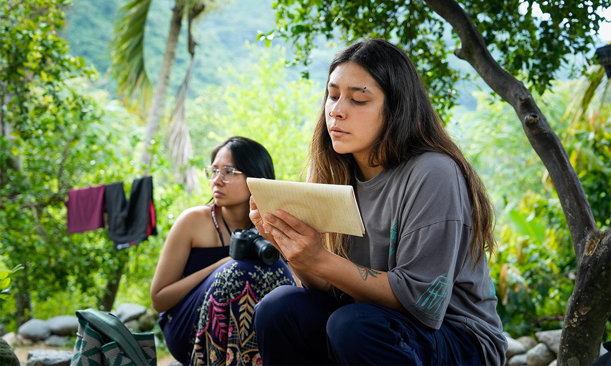Una mujer llamada Gabriela está sentada leyendo una hoja de papel en medio de la Sierra